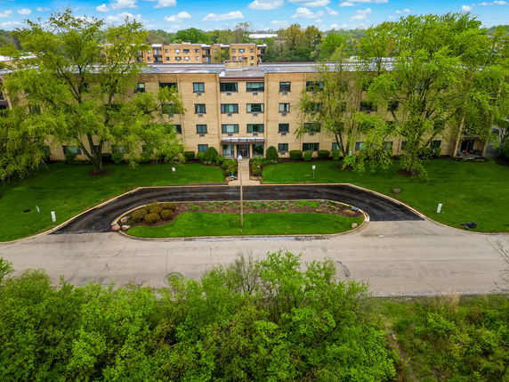 Front view of a multi-story brick building with a driveway and green lawn.