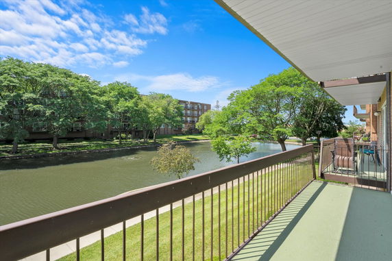 View from a balcony overlooking a pond and surrounding greenery.