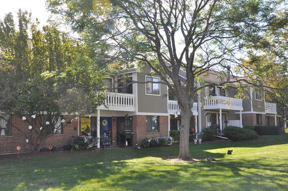 Front view of a multi-story apartment building with balconies and a brick facade.