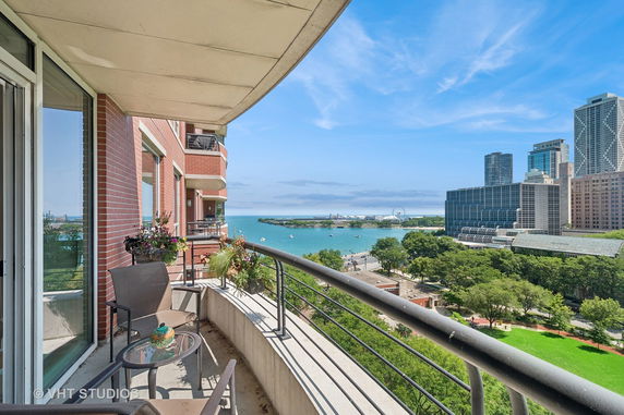 Panoramic view from a balcony overlooking a cityscape and a large body of water.