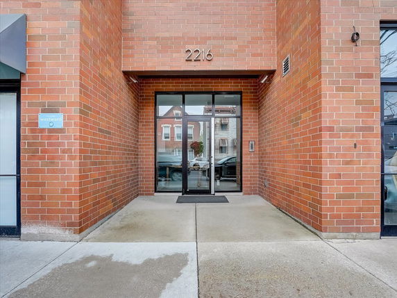 Front view of a building entrance with brick exterior walls and a glass door.