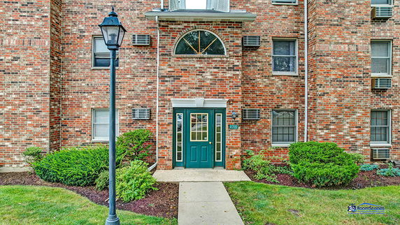 Front view of a brick multi-story building entrance with green door and windows.