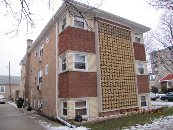 Front view of a three-story residential building with brick and lattice design.