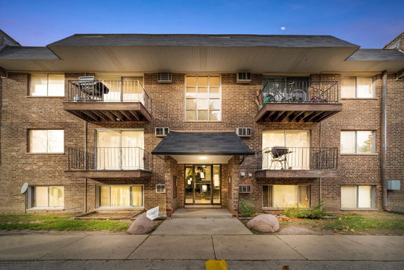 Front view of a multi-story residential building with balconies and brick facade.