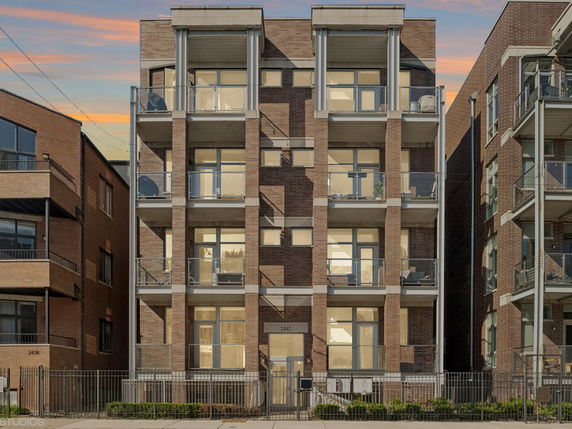 Front view of a multi-story brick apartment building with balconies.