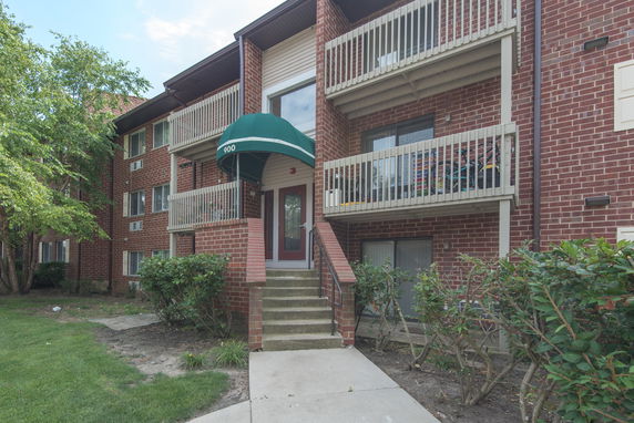 Front view of a multi-story brick apartment building with balconies.
