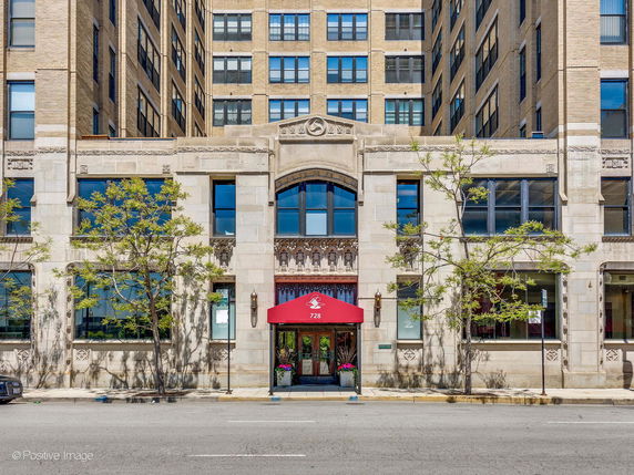 Front view of a multi-story building with decorative stonework and red awning.