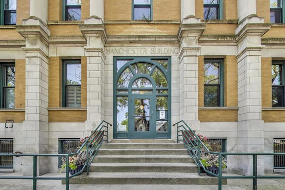 Front view of a building with a central staircase leading to an arched doorway.