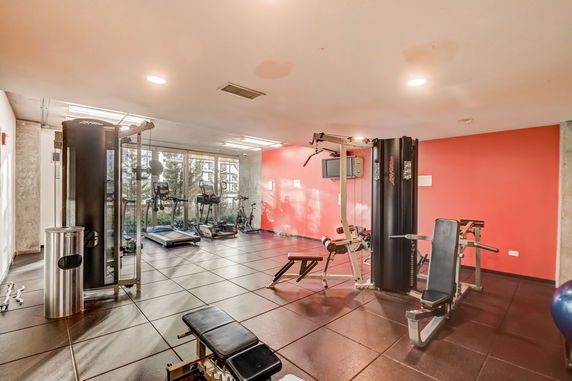 Indoor gym area with exercise equipment and large windows.