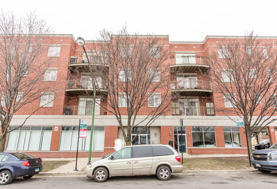 Front view of a multi-story brick building with balconies and large windows.