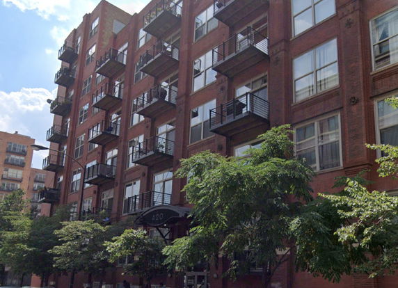 Front view of a multi-story brick apartment building with balconies.