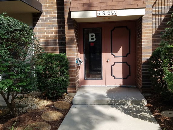 Front view of a building entrance with a brown door and brick facade.