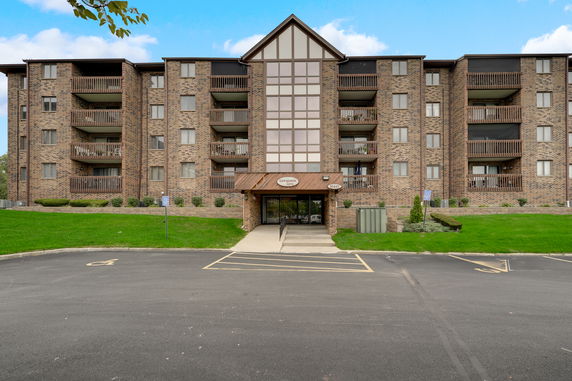 Front view of a multi-story brick apartment building with balconies.