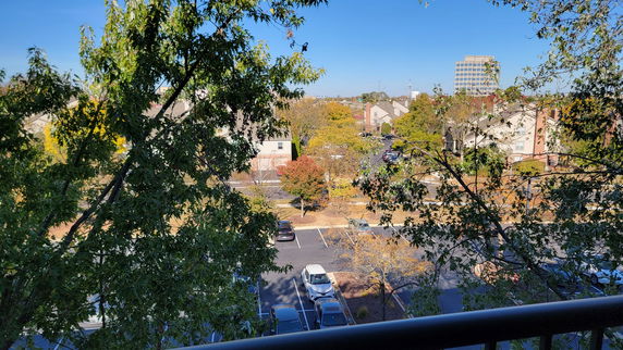 Panoramic view of a residential area with parking lot and trees.