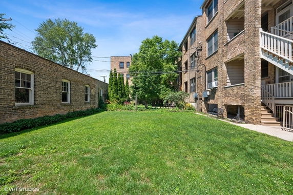 Outdoor view of brick buildings with surrounding grass and trees.