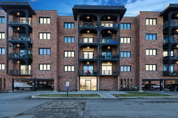 Front view of a multi-story brick apartment building with balconies.