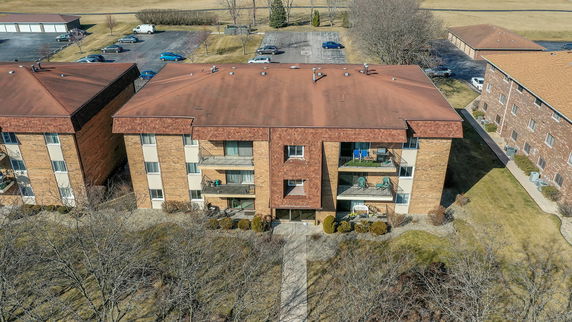 Aerial view of a three-story apartment building with a reddish-brown roof.