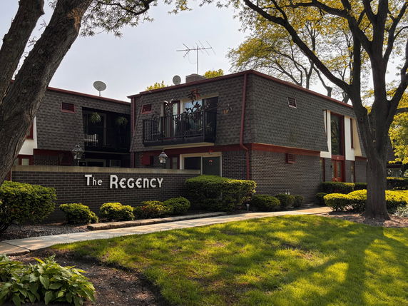 Front view of a two-story building with brick and shingle facade, featuring a sign that reads 'The Regency'.