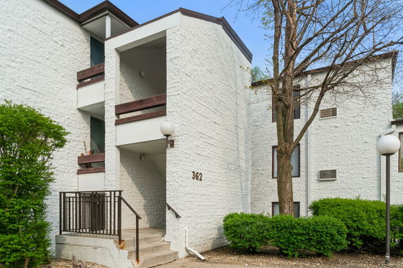 Front view of a multi-story building with white brick exterior and balconies.