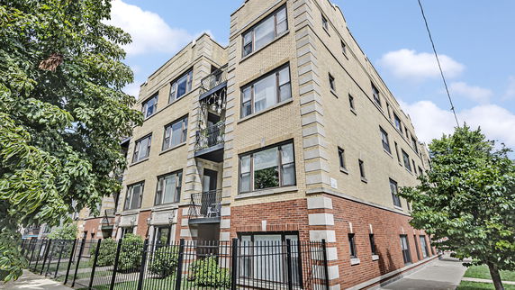 Front view of a multi-story apartment building with brick exterior and balconies.