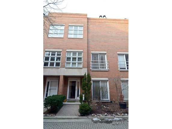 Front view of a multi-story brick townhouse with large windows.