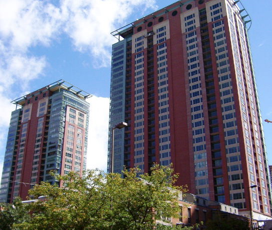 Front view of two tall apartment buildings with numerous windows and balconies.