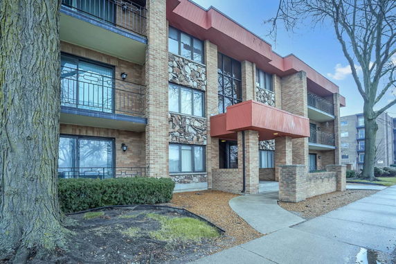 Front view of a multi-story brick apartment building with balconies.