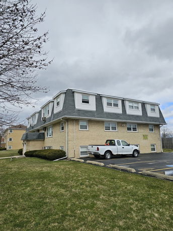 Front view of a multi-story building with a sloped roof and brick exterior.