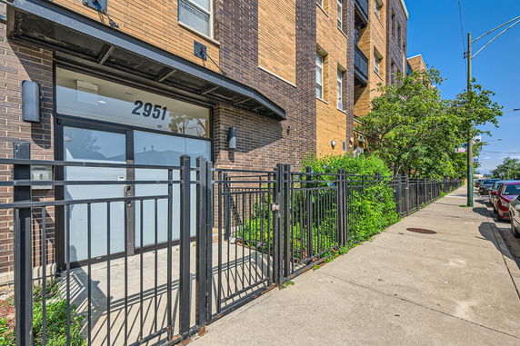 Front view of a multi-story brick building with gated entry.