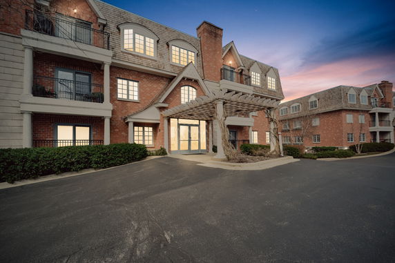 Front view of a multi-story building with brick exterior and decorative pergola at the entrance.