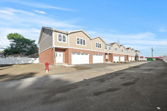 Front view of a row of modern two-story townhouses with brick and siding exteriors.