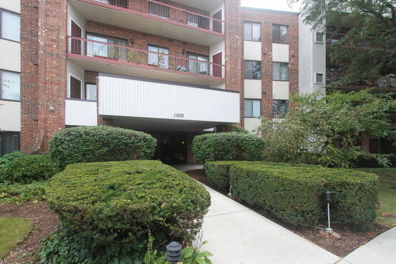 Front view of a multi-story apartment building with balconies and entrance.