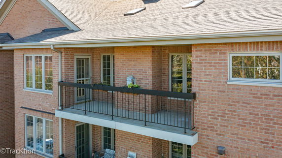 Front view of a brick house with a balcony and multiple windows.