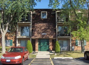 Front view of a three-story brick apartment building with balconies.