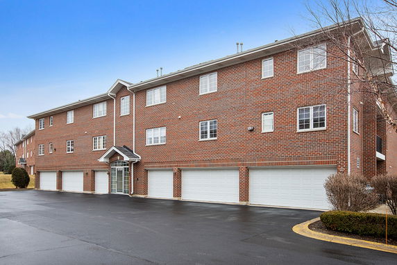 Front view of a three-story brick building with multiple garages.