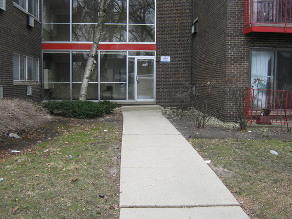 Front view of a multi-story building with glass entrance and brick exterior.