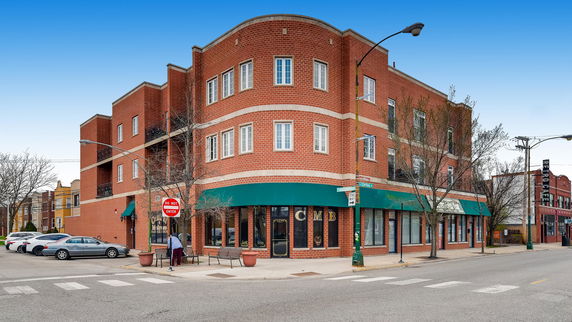 Front view of a multi-story brick commercial building on a street corner.