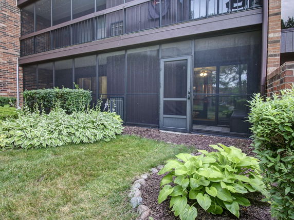 Front view of a building with screened-in balconies and a door leading outside.