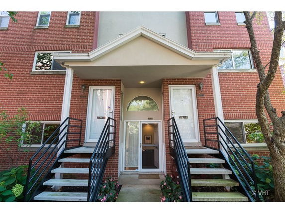 Front view of a brick apartment building with two staircases leading to separate entrances.