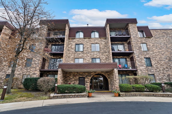 Front view of a multi-story residential building with brick exterior and balconies.