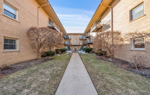 Front view of a multi-story building with balconies and a central pathway.
