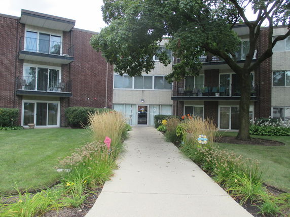 Front view of a three-story apartment building with balconies and large windows.