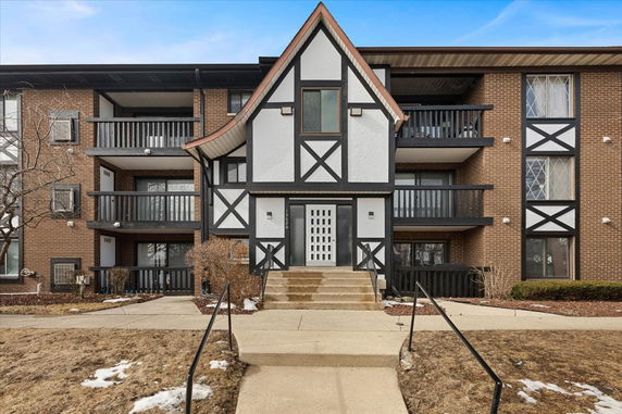 Front view of a multi-story building with a mix of brick and decorative timber elements.