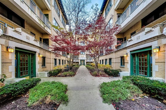 View of a multi-story apartment building with green doors and surrounding greenery.
