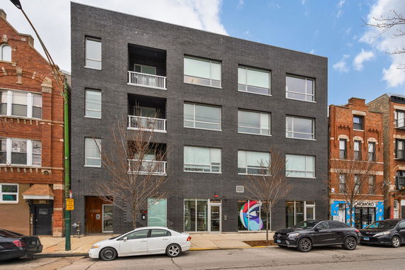 Front view of a modern four-story building with black brick facade.