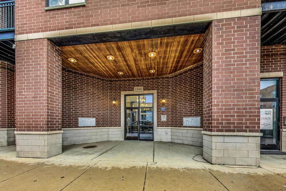 Front entrance of a building with brickwork and a wooden ceiling.