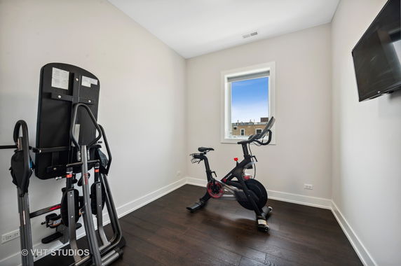 Room with exercise equipment including a stationary bike and inversion table.