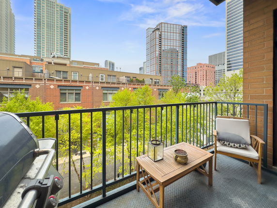 View from a balcony overlooking buildings and trees in an urban area.