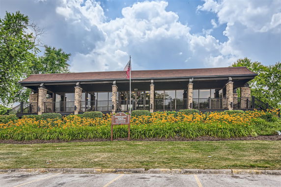 Front view of a clubhouse with a porch and stone columns.