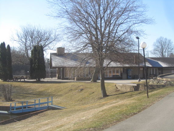 Front view of a single-story building with a sloped roof and large windows.